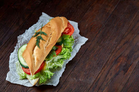 Fresh and tasty sandwich with cheese and vegetables on paper napkin over wooden background, selective focus, top viewの写真素材