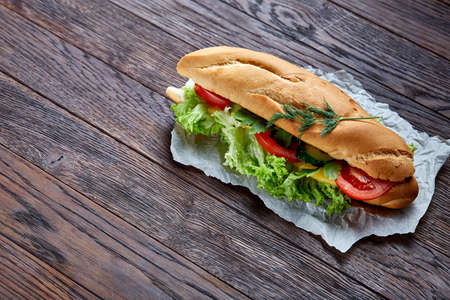 Fresh and tasty sandwich with cheese and vegetables on paper napkin over wooden background, selective focus, top viewの写真素材