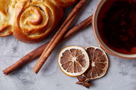 Festive composition of homemade rose bread with raisins, cup of tea, dried citrus, anise and cinnamon over white textured background, close-up, top view, shallow depth of field. Aromatic delicious pastry. Traditional sweet dessert. Food concept.の写真素材