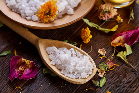 SPA concept: composition of spa treatment with natural sea salt, aromatic oil and flowers on wooden background, close up, top view, selective focus, shallow depth of field. Dayspa cosmetics products. Spa natural concept. Spa and wellness setting.の写真素材
