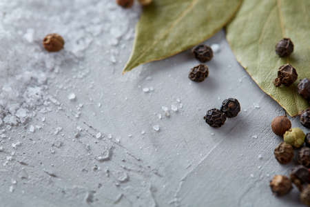 Composition of bay laurel leaf with peppercorn and salt isolated on dark background, top view, close-up, selective focus. Aroma collection culinary herbs and spices. Organic condiment. Food background.の写真素材