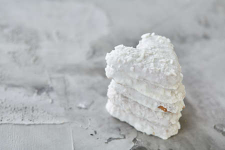 Sweet crunchy coconat heart-shaped biscuits arranged in pattern on light textured background, top view, close-up, shallow depth of field, selective focus, vertical. Yummy and crunchy dessert. Artistic pattern. Delicious snack. Breakfast background.の写真素材