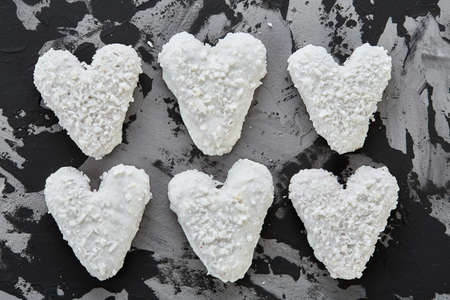 Sweet crunchy coconat heart-shaped biscuits arranged in pattern on light textured background, top view, close-up, shallow depth of field, selective focus, vertical. Yummy and crunchy dessert. Artistic pattern. Delicious snack. Breakfast background.の写真素材