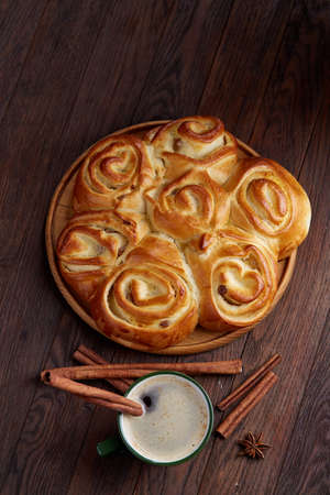 Creamy coffee in cup with homemade rose bread on vintage wooden background, close-up, selective focusの写真素材