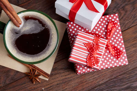 Still life with cup of coffee holiday gift in small red color box with ribbon and bow on wooden background, top view, close-upの写真素材
