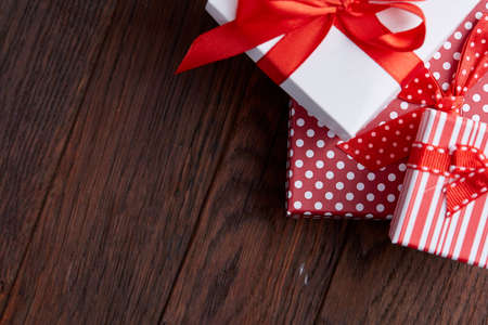Still life with holiday gift in small red color box with ribbon and bow on wooden background, top...