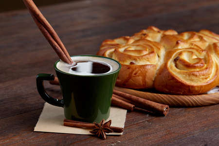 Creamy coffee in cup with homemade rose bread on vintage wooden background, close-up, selective focusの写真素材