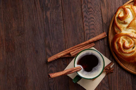 Creamy coffee in cup with homemade rose bread on vintage wooden background, close-up, selective focusの写真素材