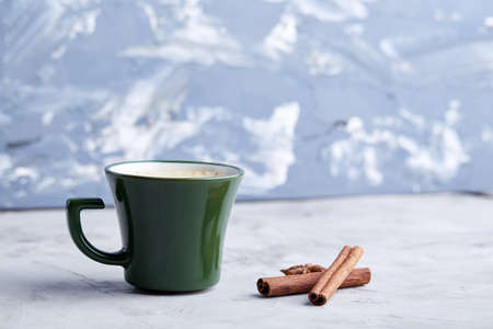 Cup of creamy coffee with cinnamon and star anise on a white textured background, top view, close-up, selective focusの写真素材