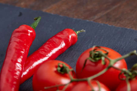 Vegetarian still life with fresh grape tomatoes, pepper and salt in wooden spoon on wooden background, selective focusの写真素材