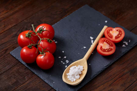 Vegetarian still life with fresh grape tomatoes, pepper and salt in wooden spoon on wooden background, selective focusの写真素材