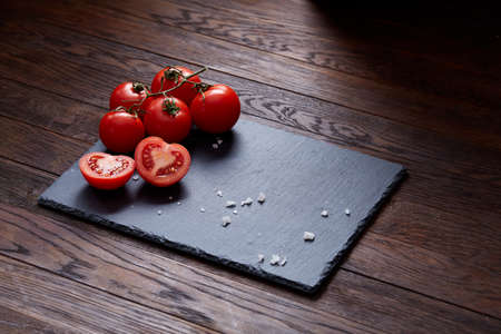 Vegetarian still life with fresh grape tomatoes, pepper and salt in wooden spoon on wooden background, selective focusの写真素材
