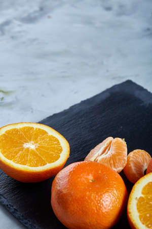 High angle still life view of sliced ruby orange and tangerine arranged together on stony boardの写真素材