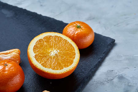 High angle still life view of sliced ruby orange and tangerine arranged together on stony boardの写真素材