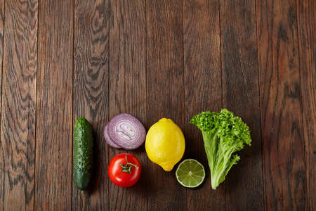 Fresh vegetables still life. Veges lined up on a wooden background, top view, close-up, selective focus, copy space.の写真素材