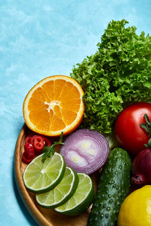 Still life of fresh organic vegetables on wooden plate over blue background, selective focus, close-upの写真素材