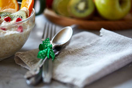 Breakfast still life with oatmeal porridge and fruits, served with fork and spoon, shallow depth of field.の写真素材