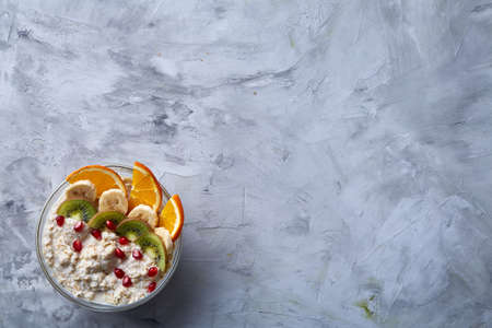 Delicious oatmeal with fruits in glass bowl isolated on white textured background, copy space,...