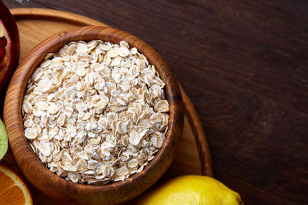 Bowl with oatmeal flakes served with fruits on wooden tray wooden background, flat lay, selective...