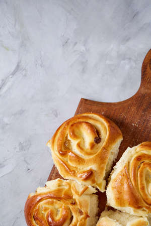 Homemade rose buns on wooden cutting board over white textured background, close-up, shallow depth of fieldの写真素材