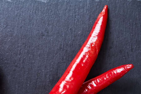 Fresh red hot pepper on a black background, top view, close-up, selective focus.