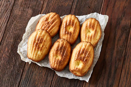 Sweet almond cookies put in rows on white paper over wooden background, close-up, selective focusの写真素材