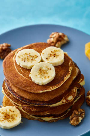 Pile of homemade pancakes with banana and walnuts on blue background, selective focusの写真素材