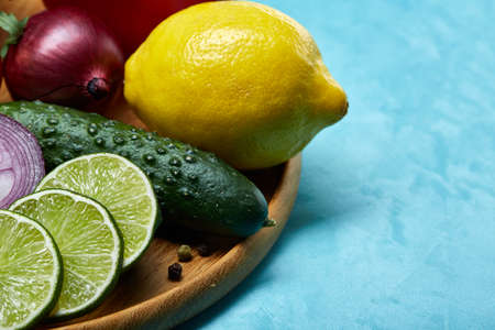 Colorful still life of fresh organic fruits and vegetables on wooden plate over blue background, selective focus, close-up. Vegetable set. Pile of great variety of fresh organic vegetables. Creative composition. Healthy lifestyle concept.の写真素材