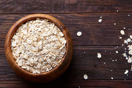 Diet breakfast oatmeal with fruits, bowl and spoon with oat flakes, selective focus, close-up