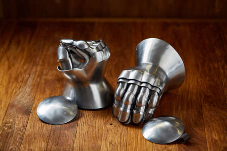 Medieval armor, detail of an ancient armor. Steel gloves on wooden background.の写真素材