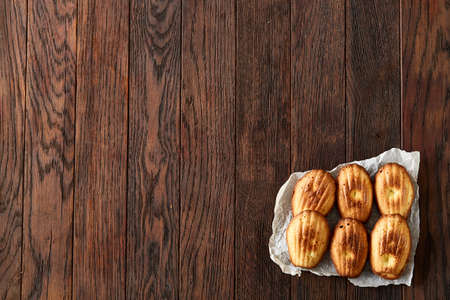 Sweet almond cookies arranged in rows on white piece of paper over vintage wooden background,...