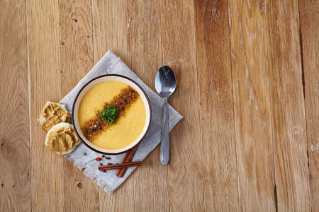 Purple bowl of creamy pumpkin soup garnished with dill, served with toasted bread slices covered with paste on homespun napkin over rustic background, closeup, selective focus, topview. Dietary vegetable food. Traditional fall and winter dishes.の写真素材