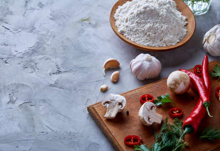 Composition of fresh hot pepper, mushrooms, dill and garlic on cutting board, plate with cooking salt over white textured background, close-up, selective focus. Ingredients ready to make salad. Delicious countryside still life. Food concept.の写真素材