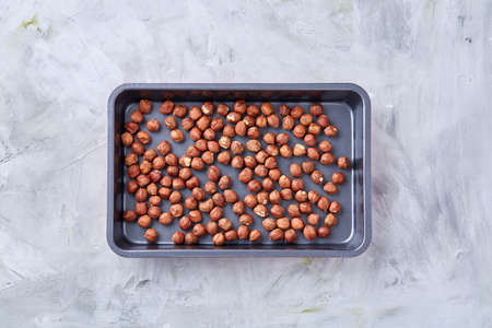 Hazelnut on cooking tray over white textured background, close-up, selective focus, shallow depth of field. Some copy space for your inscription. Nutritious organic snack. Vegetarian protein. Seasonal antioxidant. Healthy food concept.の写真素材