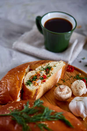 Countryside still life with delicious rustic pastries, cup of coffee, herbs and vegetables on a wooden cutting board over a vintage wooden background, selective focus. Yummy puffy meal. Tasty cobbler. Homemade appetizer.の写真素材
