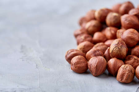 Raw hazelnut on heap isolated on white textured background, close-up, selective focus, shallow depth of field. Some copy space for your inscription. Nutritious organic snack. Vegetarian protein. Seasonal antioxidant. Healthy food concept.の写真素材