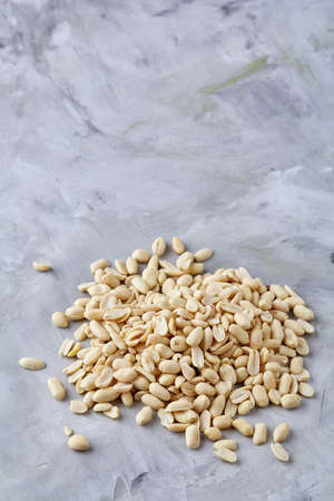 Pile of peelled peanuts isolated on white textured background, background, top view, close-up, selective focus, vertical. Some copy space. Organic nutritious ingredient. Gourmet appetizer. Tasty roast snack. Food concept.の写真素材