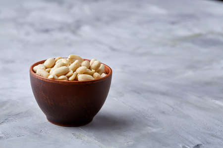 Shelled peanuts in ceramic bowl isolated over white textured background, top view, close-up. Some copy space. Organic nutritious ingredient. Gourmet appetizer. Tasty roast snack. Healthy food conceptの写真素材