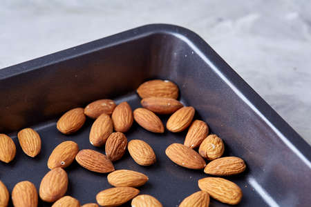 Raw almond on baking tray over white textured background, selective focus, shallow depth of field. Ready to cook. Healthful and nutritious snack. Delicious ready to cook nuts. Healthy lifestyle concept.の写真素材