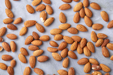 Seamless pattern with almond on the gray background, flat lay, close-up. Studio shot. Uncooked protein. Natural oil source. Diet ingredient for weight control. Healthy food concept.の写真素材