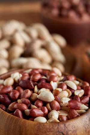 A composition from different varieties of nuts in wooden bowl on rustic background: almonds, peanuts. Close-up, selective focus, shallow depth of field. Delicious nutritious mix. Organic antioxidant. Dieting assortment. Healthy food concept.の写真素材