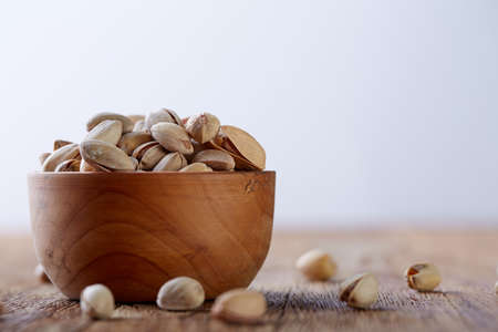 Almonds in brown bowl on wooden table over white background, top view, selective focus. Some copy space. Tasty organic snack. Healthy food for healthy life. Food concept. Natural nutritious nut. Delicious appetizer.の写真素材