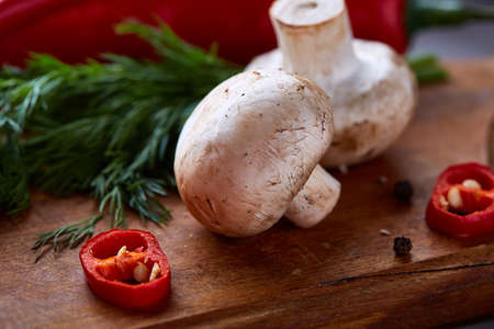 Composition of fresh hot pepper, mushrooms, dill and garlic on cutting board, plate with cooking salt over white textured background, close-up, selective focus. Ingredients ready to make salad. Delicious countryside still life. Food concept.の写真素材