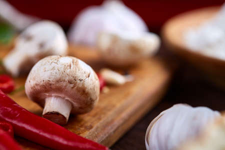 Composition of fresh hot pepper, mushrooms, dill and garlic on cutting board, plate with cooking salt over white textured background, close-up, selective focus. Ingredients ready to make salad. Delicious countryside still life. Food concept.の写真素材
