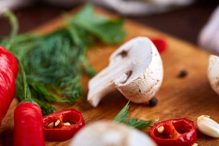 Composition of fresh hot pepper, mushrooms, dill and garlic on cutting board, plate with cooking salt over white textured background, close-up, selective focus. Ingredients ready to make salad. Delicious countryside still life. Food concept.の写真素材