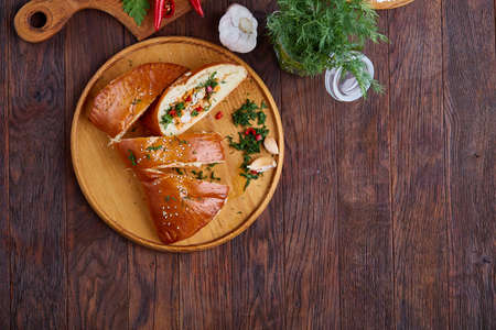 Countryside cuisine still life with tasty homemade pie, fresh mushrooms, hot pepper, garlic and herbs on wooden cutting board over white textured background, selective focus. Studio shot. Delicious rustic appetizer. Food concept.の写真素材