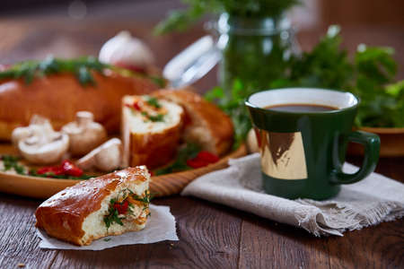 Countryside still life with delicious rustic pastries, cup of coffee, herbs and vegetables on a wooden cutting board over a vintage wooden background, selective focus. Yummy puffy meal. Tasty cobbler. Homemade appetizer.の写真素材