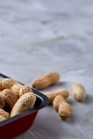 Unpeeled raw peanut on baking tray over white textured background, selective focus, shallow depth of field. Ready to bake. Healthful and nutritious snack. Delicious ready to cook nuts. Healthy lifestyle concept.の写真素材