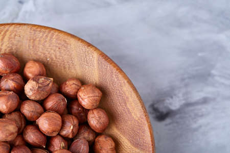 Hazelnuts in wooden bowl on white textured background with copy space, top view, close-up, selective focus, shallow depth of field. Nutritious organic snack. Vegetarian protein. Seasonal antioxidant. Healthy food concept.の写真素材