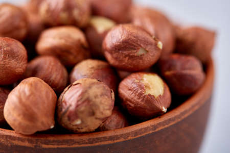 Hazelnuts in wooden bowl on white textured background with copy space, top view, close-up, selective focus, shallow depth of field. Nutritious organic snack. Vegetarian protein. Seasonal antioxidant. Healthy food concept.の写真素材